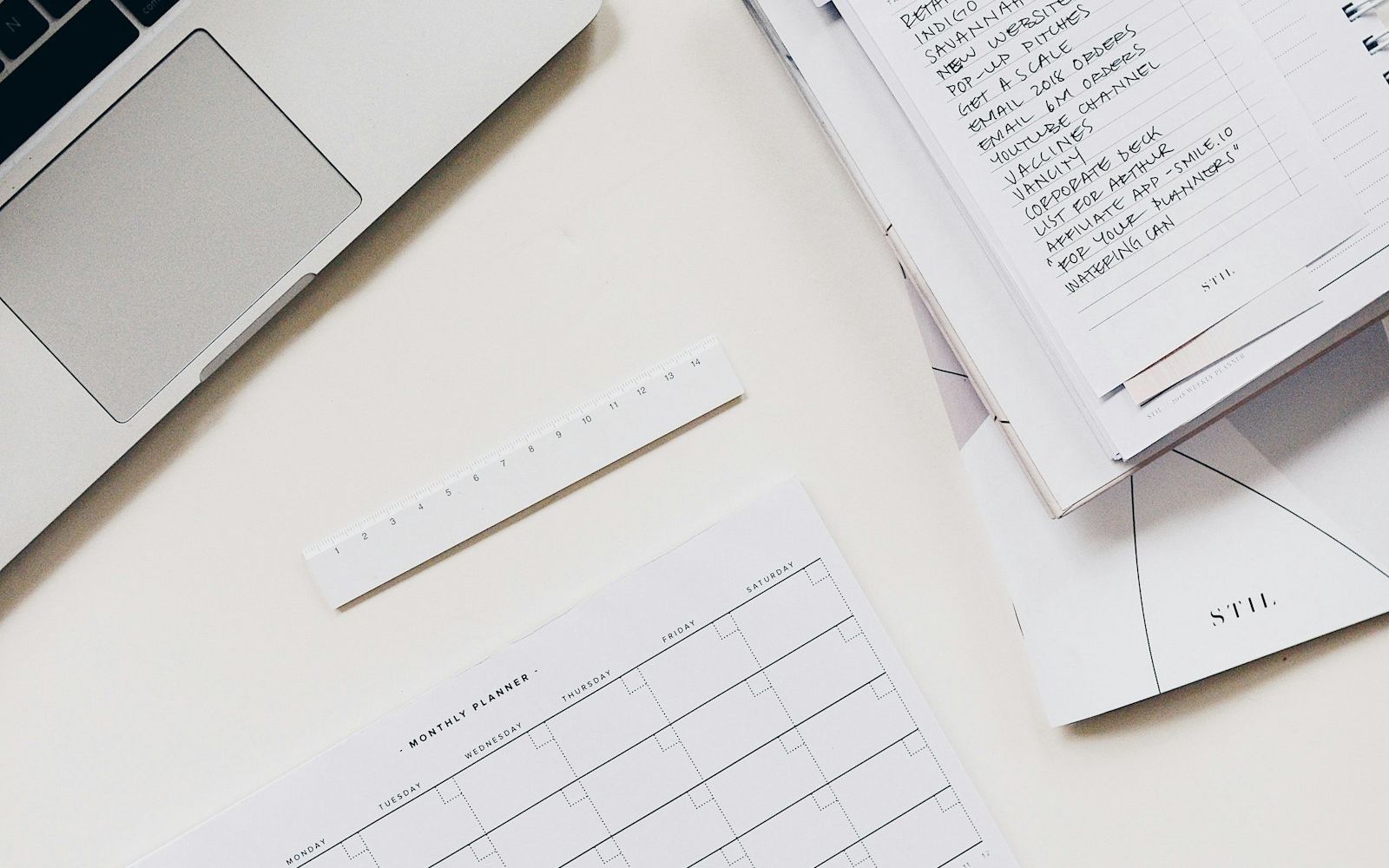 A laptop beside a notebook.