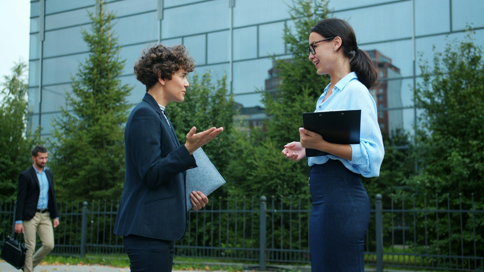 Two colleagues talking outside a modern building.
