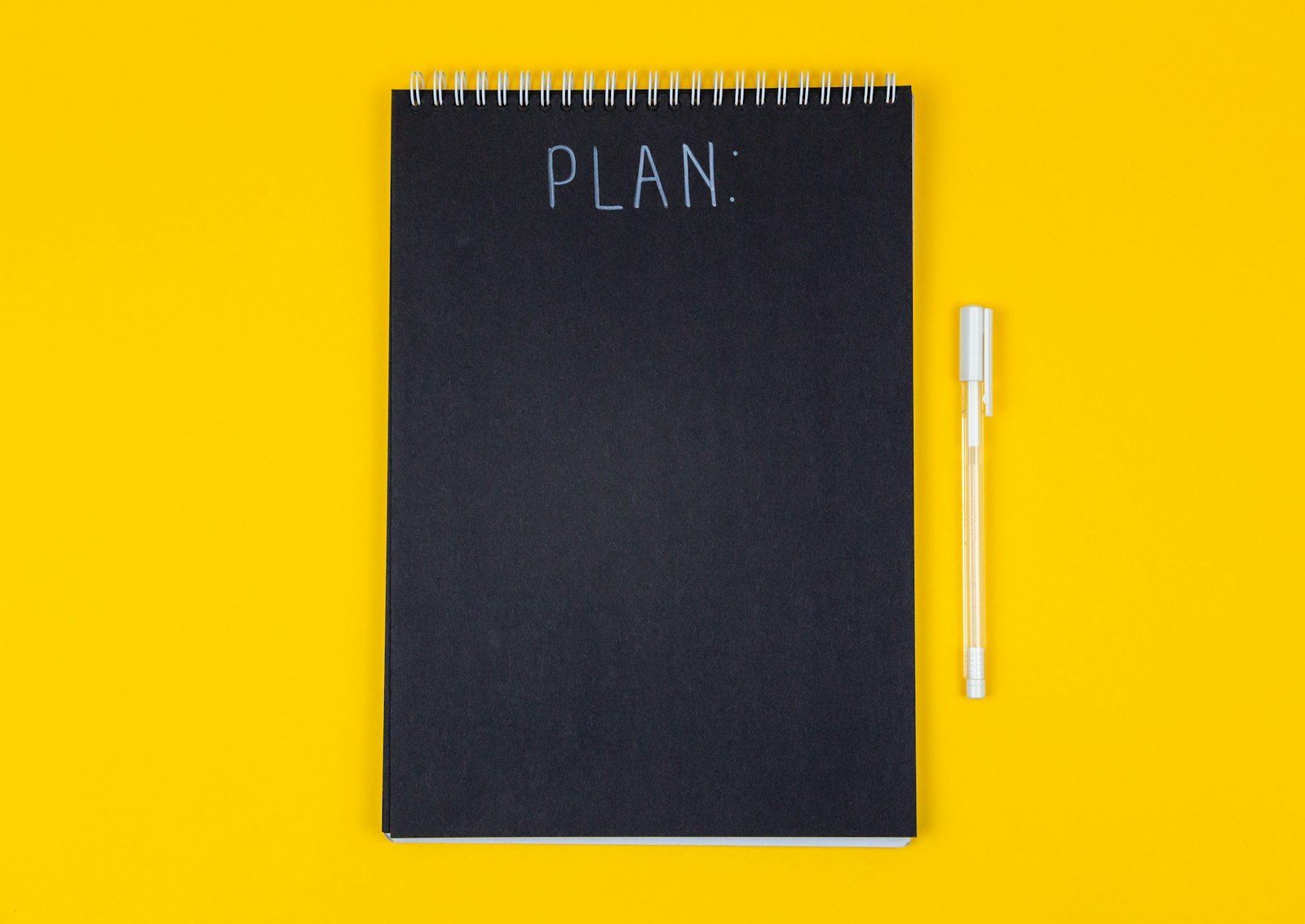 A notebook with the word Plan on a yellow background.