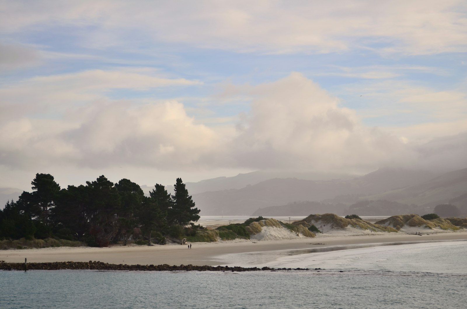A calm bay surrounded by mountains and trees.