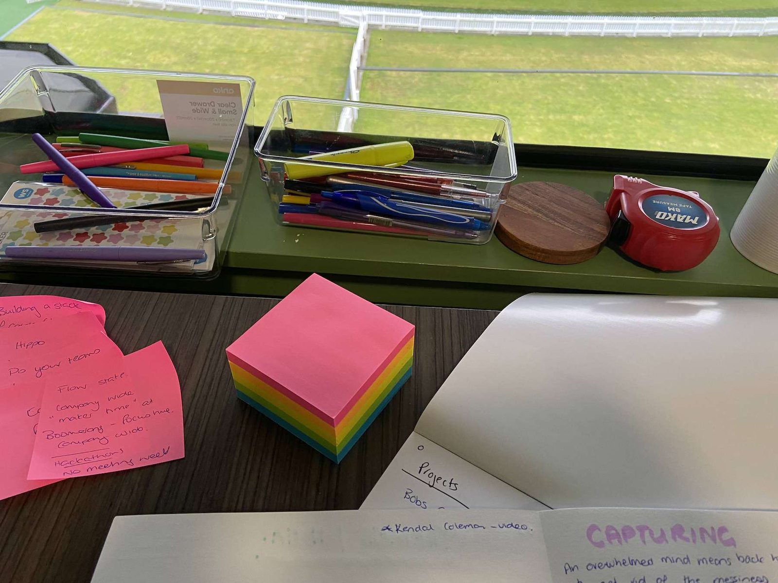 Notebook open at Capturing, sticky notes and pens on the desk.